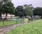 A photo of the children's play area at Salthouse Fields in Clevedon. The image shows a gated area with swings, a climbing frame and other play equipment.