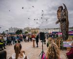 The High Sheriff stands in the shadow of the Knife Angel, talking to the assembled crowd. Birds fly overhead