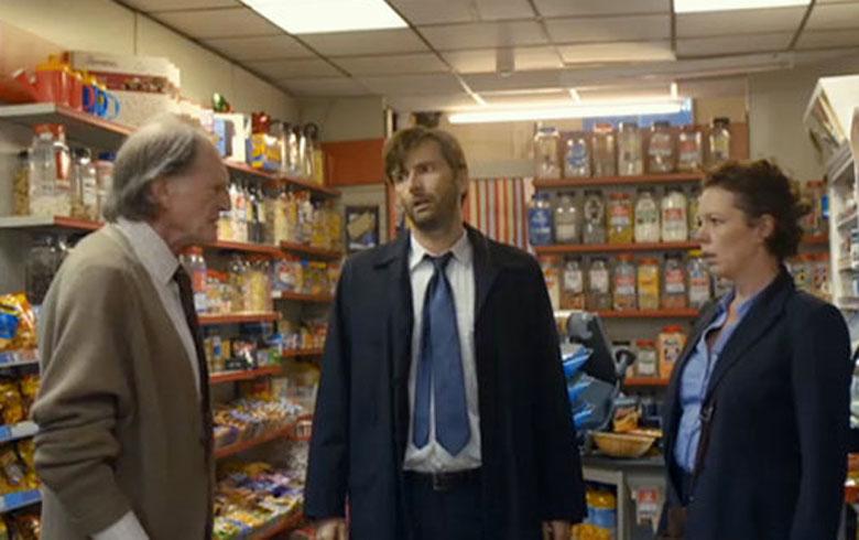 Actors David Bradley, David Tennant and Olivia Coleman standing inside a corner shop talking to each other