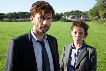 David Tennant and Olivia Coleman face the camera while standing in an open green field
