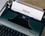 An old green typewriter with a piece of paper in it with the word News typed on it