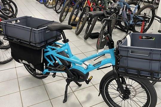 image of an electric cargo bike colour light blue with carrying boxes front and rear