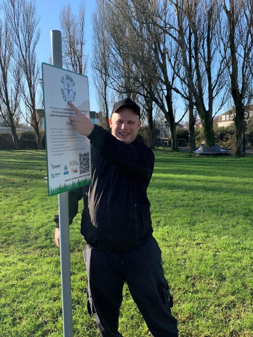 A photo to show David Connolly, who came up with the idea for the gym, pointing at a sign which includes the logo he designed.