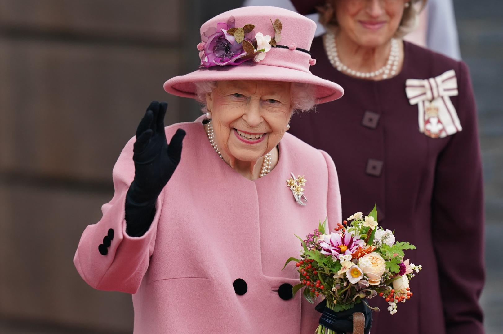 Her Majesty The Queen holding flowers and waving
