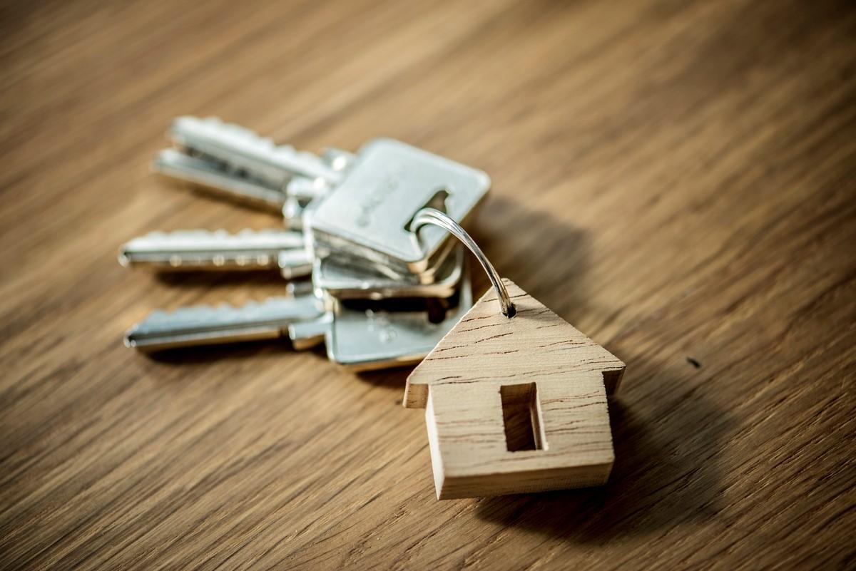 close up of a key ring in the shape of a house with keys on a wooden table