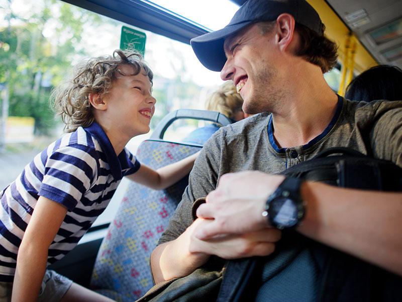 Man and his son on a bus - they are grinning at each other