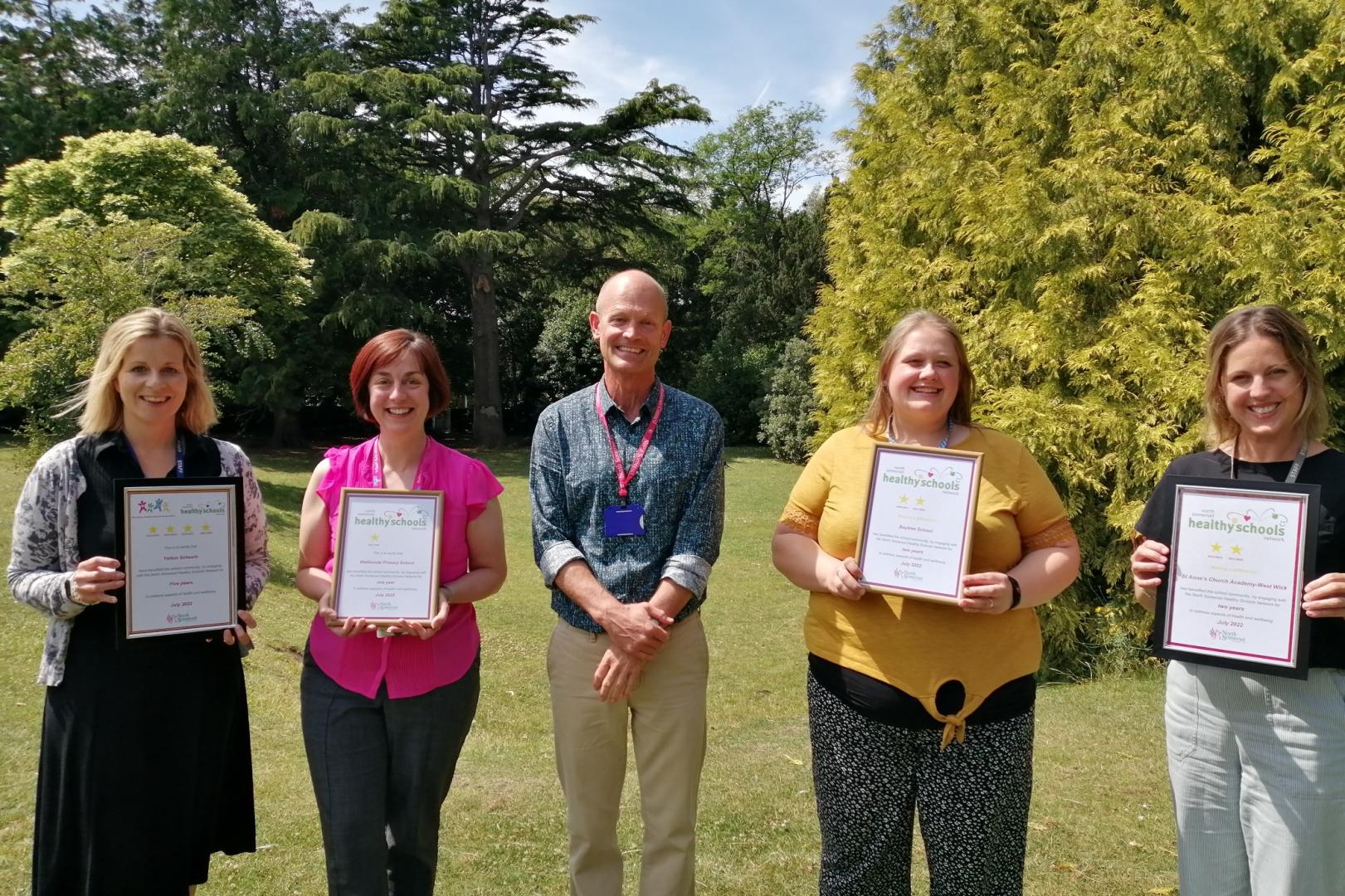 Four people holding certificates with a member of council staff