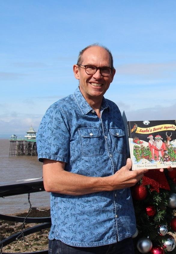 A photo of author and illustrator Steve Gunning holding his book Santa's Secret Agents