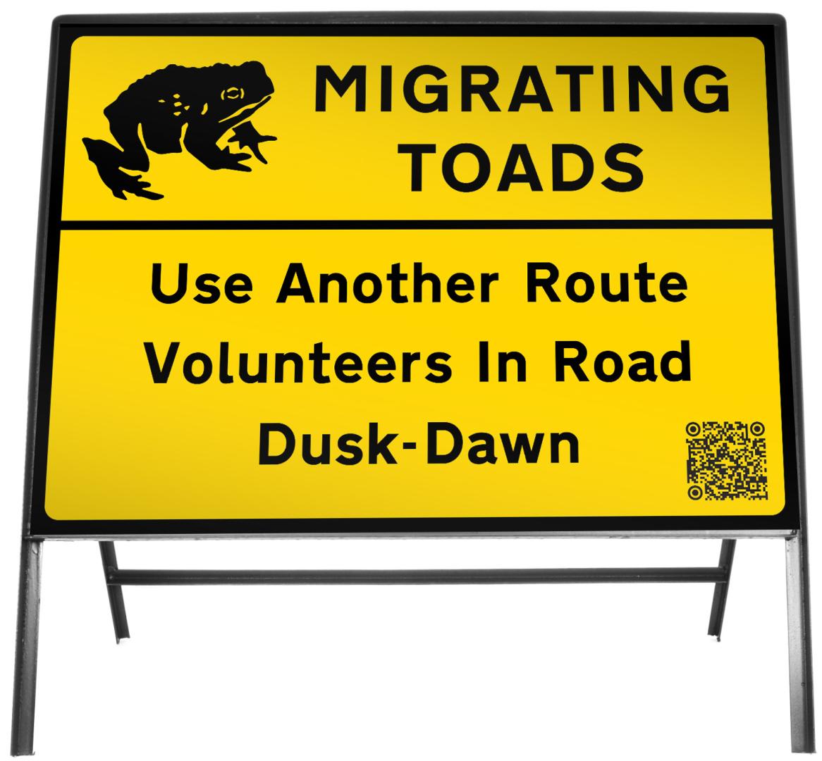 A photo of a road sign which reads migrating toads use another route volunteers in road dawn to dusk.