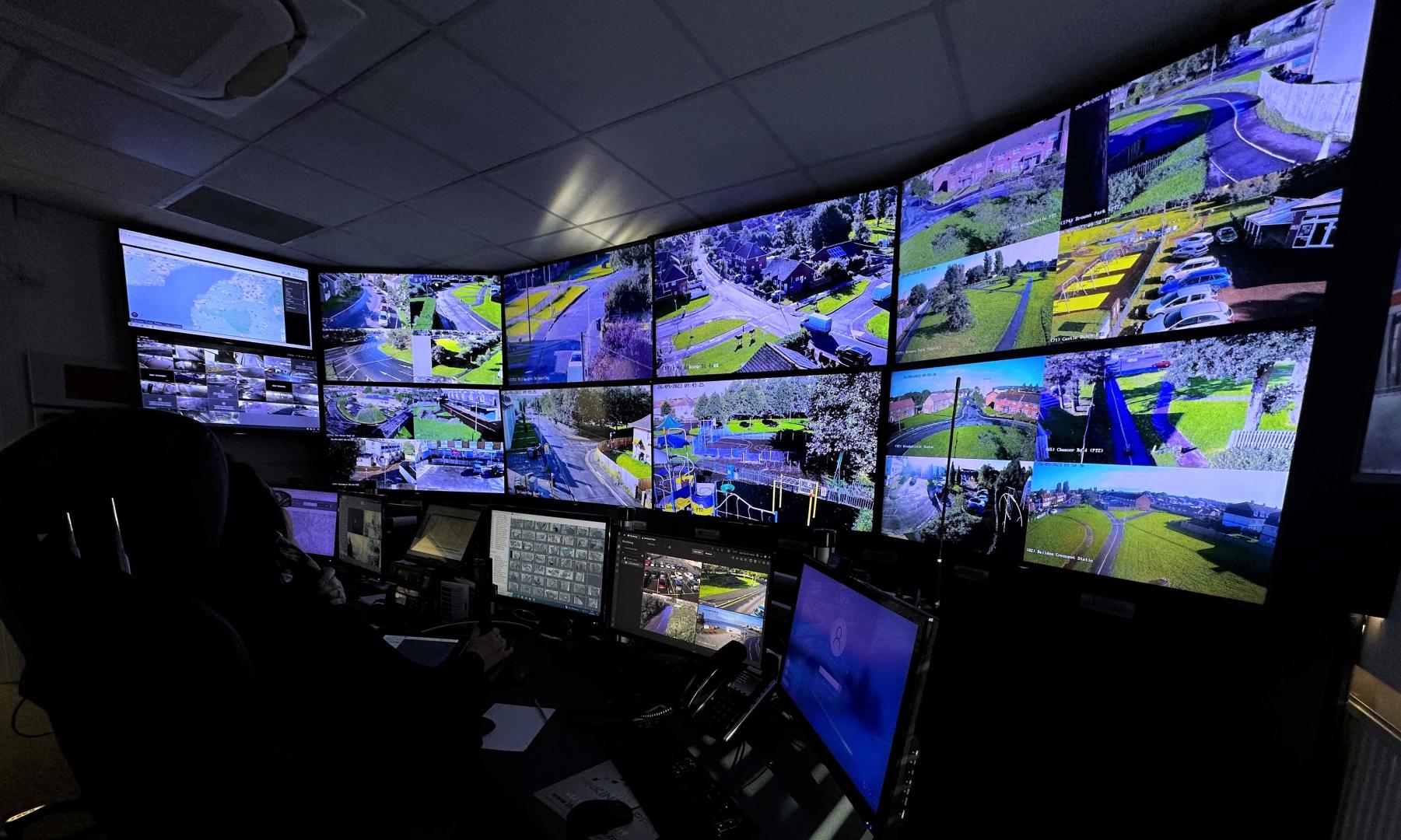 A photo of the inside of North Somerset Council's CCTV control room showing a person at a desk looking at multiple screens