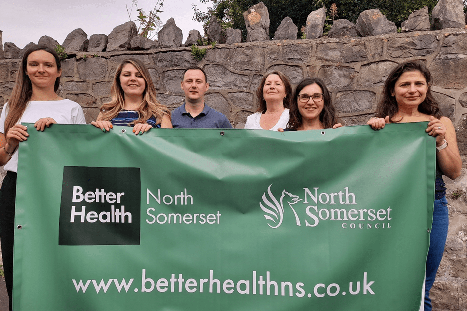 Six people stood behind a banner which has Better Health North Somerset written on it.