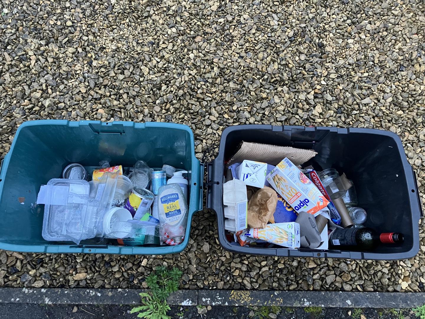 Two full recycling boxes on top of gravel. The right-hand box contains mixed paper and cardboard